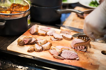 Chef Slicing Cooked Meat on Wooden Cutting Board