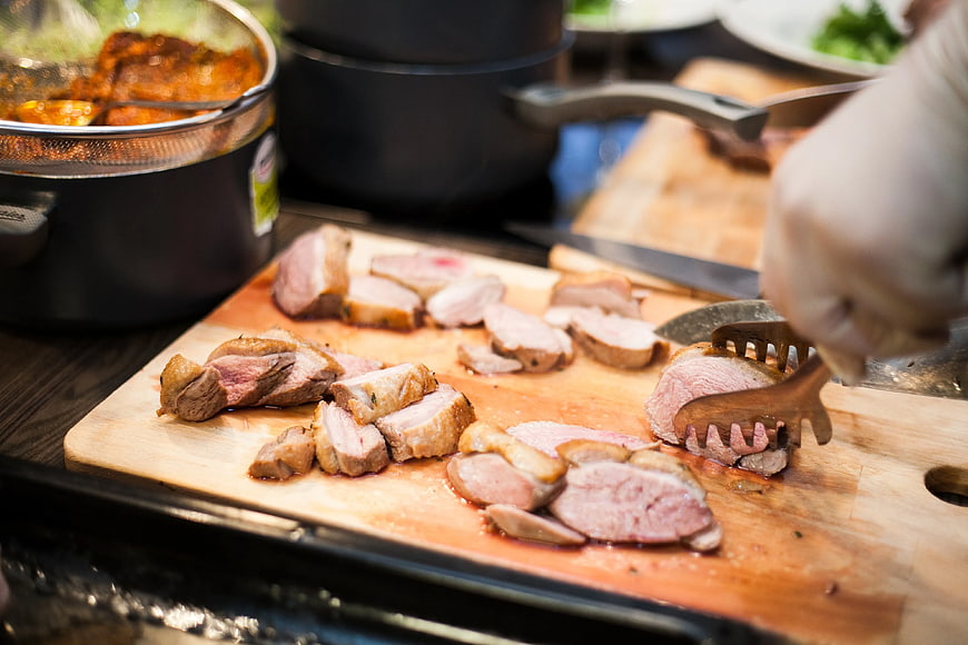 Chef Slicing Cooked Meat on Wooden Cutting Board