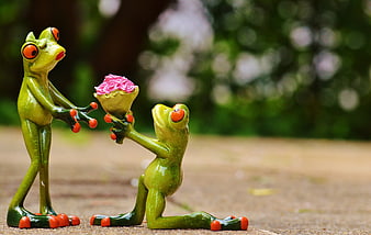 Cute frog figurines proposing with pink roses in garden