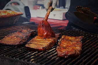 Close-up of BBQ ribs being glazed with sauce on a grill