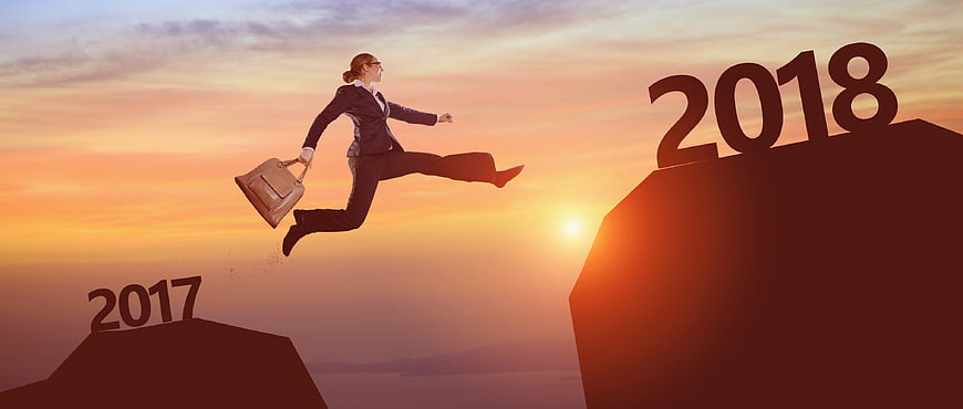 Businesswoman jumping from 2017 to 2018 cliff at sunset