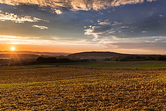 Golden Sunset Over Rolling Hills and Harvested Fields