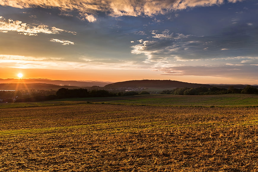 Golden Sunset Over Rolling Hills and Harvested Fields