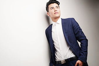 Handsome Asian man in blue suit looking up against white background