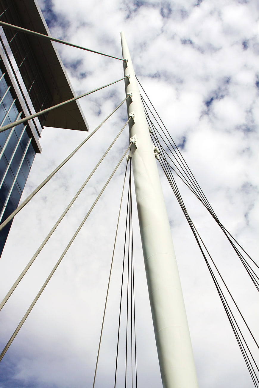 Low angle view of modern cable-stayed bridge tower against cloudy sky