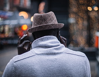 Man in Fedora Talking on Phone with City Bokeh Background