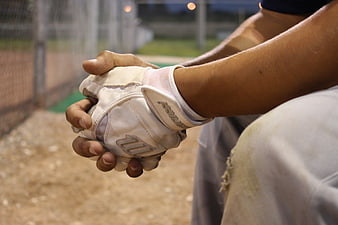 Baseball player adjusting batting gloves on the bench
