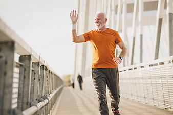 Active Senior Man Running and Waving on Bridge