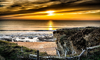 Dramatic Golden Sunset Over Ocean Cliffs and Sandy Beach