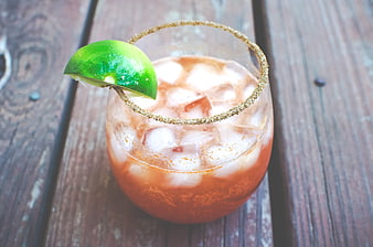 Michelada cocktail with lime wedge on rustic wooden table
