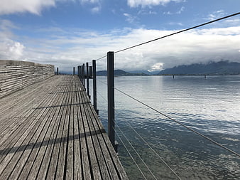 Wooden pier extending over Lake Zurich with mountains