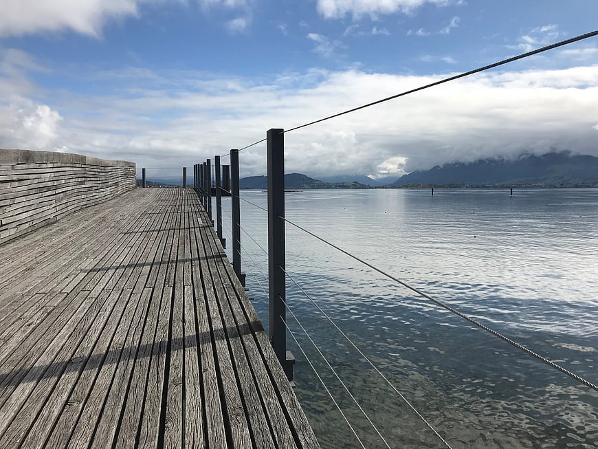 Wooden pier extending over Lake Zurich with mountains