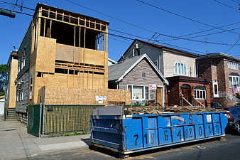 House under construction with blue dumpster on urban street