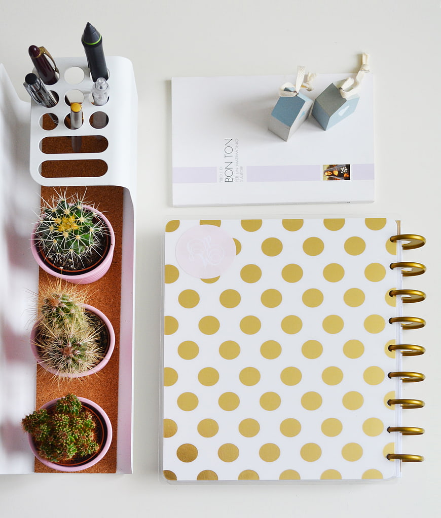 Flat lay of gold polka dot planner, cacti, and desk organizer