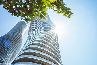 Low angle view of modern curved skyscrapers with sun flare