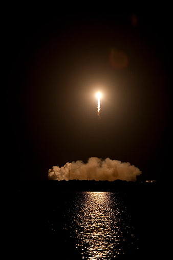 Night rocket launch with water reflection and smoke