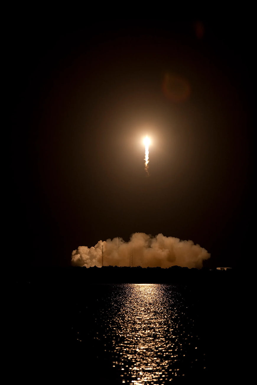 Night rocket launch with water reflection and smoke