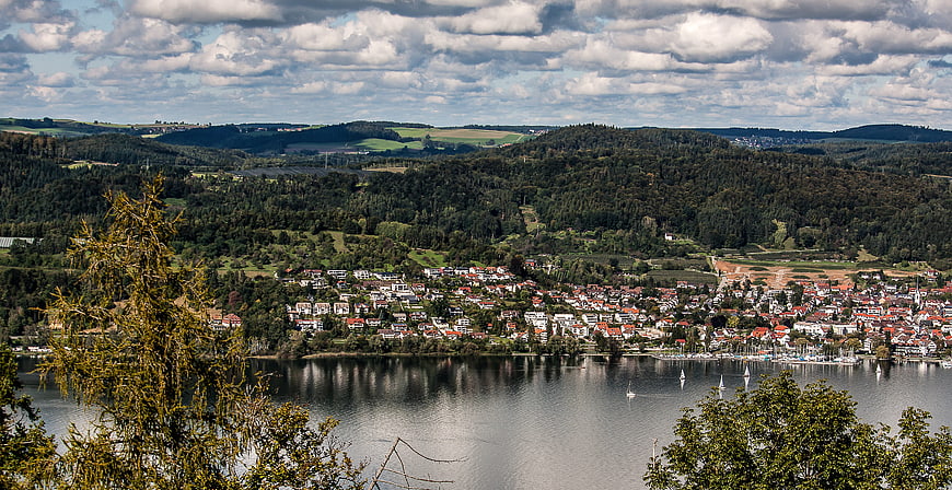Panoramic view of a lakeside village with forested hills