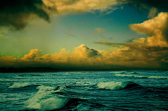 Dramatic Ocean Waves Under Golden Clouds at Dusk