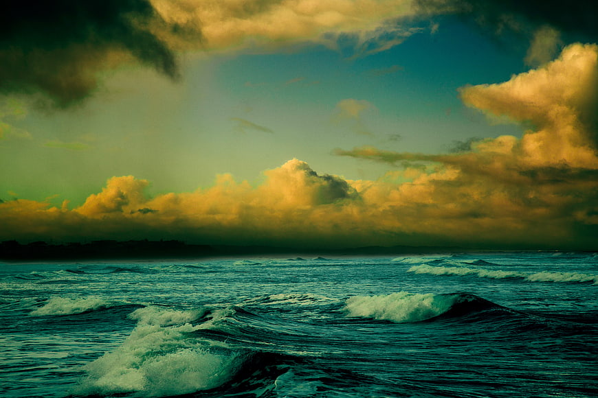 Dramatic Ocean Waves Under Golden Clouds at Dusk
