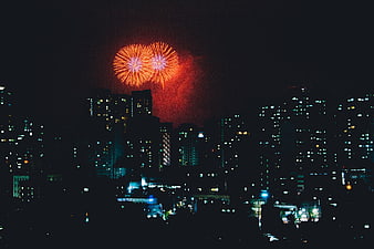 Red fireworks exploding over a dark city skyline at night
