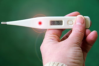 Hand holding digital thermometer showing 38.75 fever reading