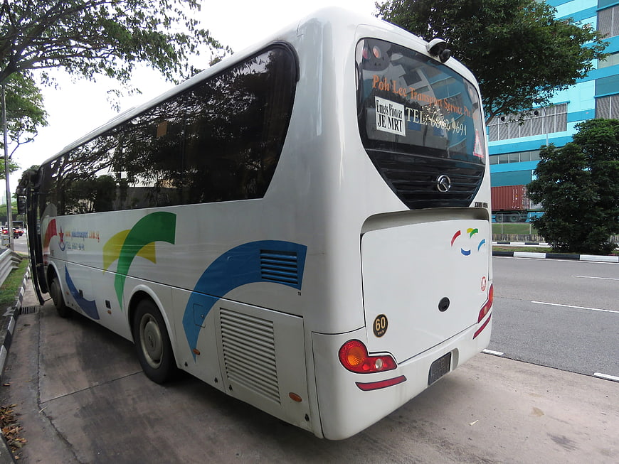 Rear View Of White Tour Bus Parked On Urban Street