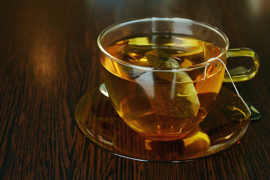 Steaming Glass Cup of Herbal Tea on Wooden Table
