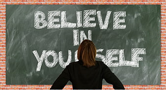 Woman facing chalkboard with believe in yourself text