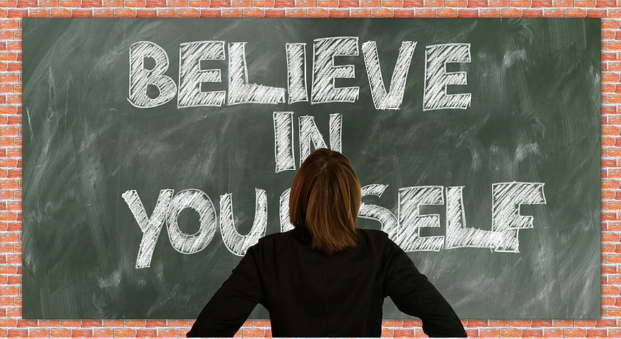 Woman facing chalkboard with believe in yourself text