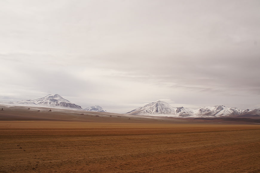 Vast Highland Landscape with Snow-Capped Mountains and Overcast Sky