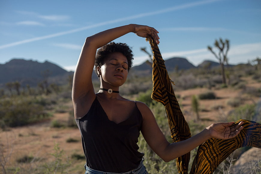 Woman meditating with flowing scarf in desert landscape
