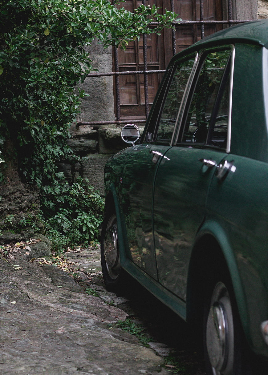 Vintage Green Car Parked on Cobblestone Street