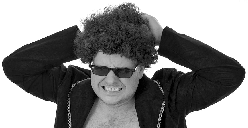 Funny man with curly hair and sunglasses pulling his hair in frustration