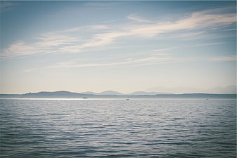 Serene Lake Landscape with Distant Mountains and Sailboats