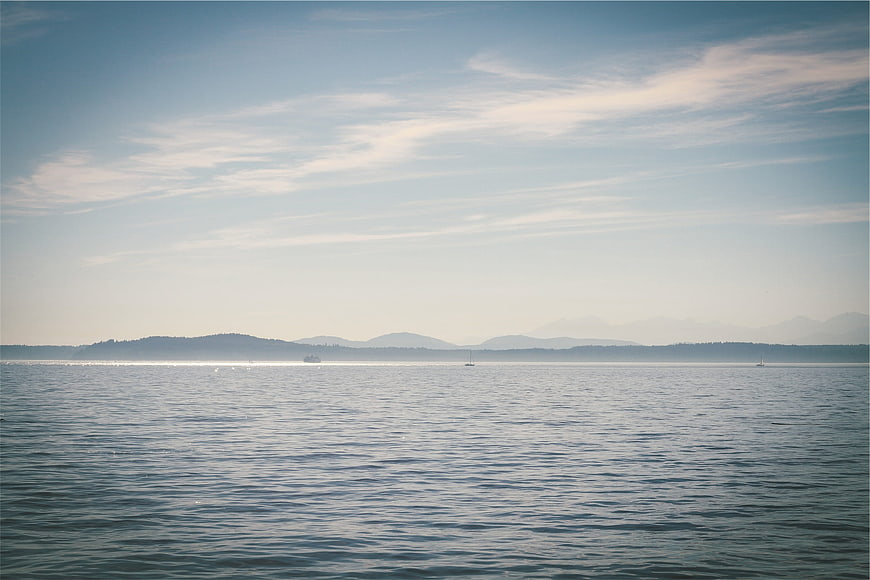 Serene Lake Landscape with Distant Mountains and Sailboats