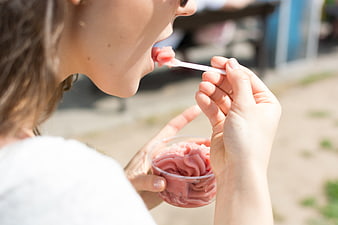 Woman eating pink strawberry sorbet outdoors in summer