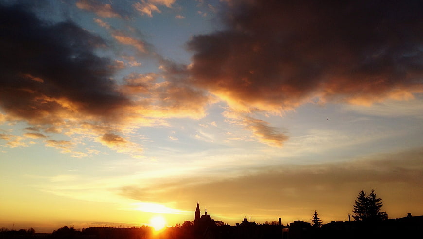 Dramatic sunset over town silhouette with golden clouds