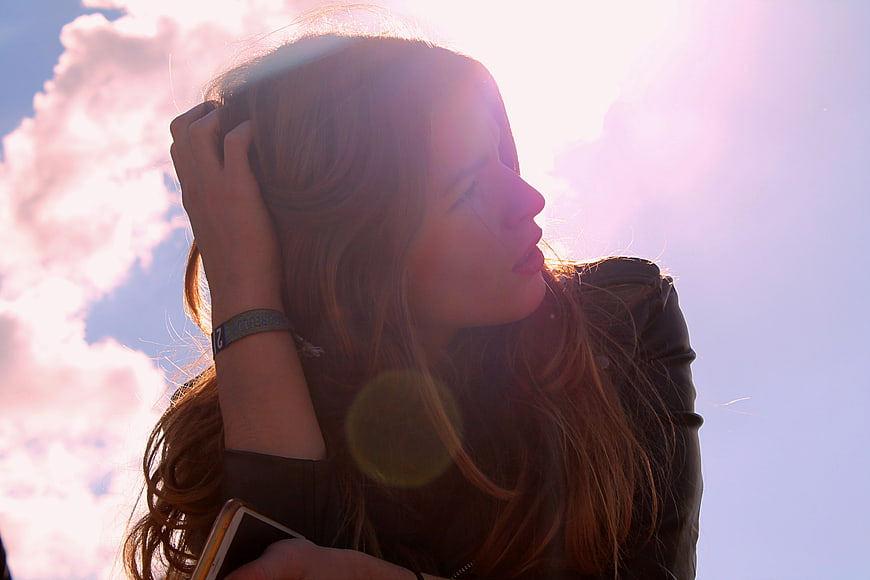 Young woman with red hair looking up into bright sunlight