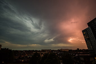 Dramatic lightning bolt striking over urban cityscape at dusk