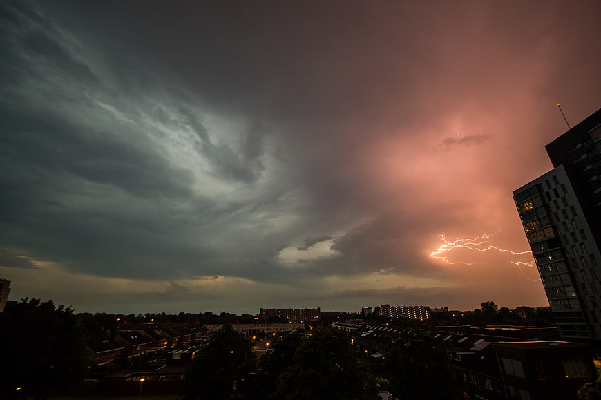 Dramatic lightning bolt striking over urban cityscape at dusk