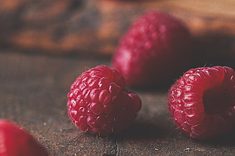 Close-up of fresh raspberries on rustic wooden surface