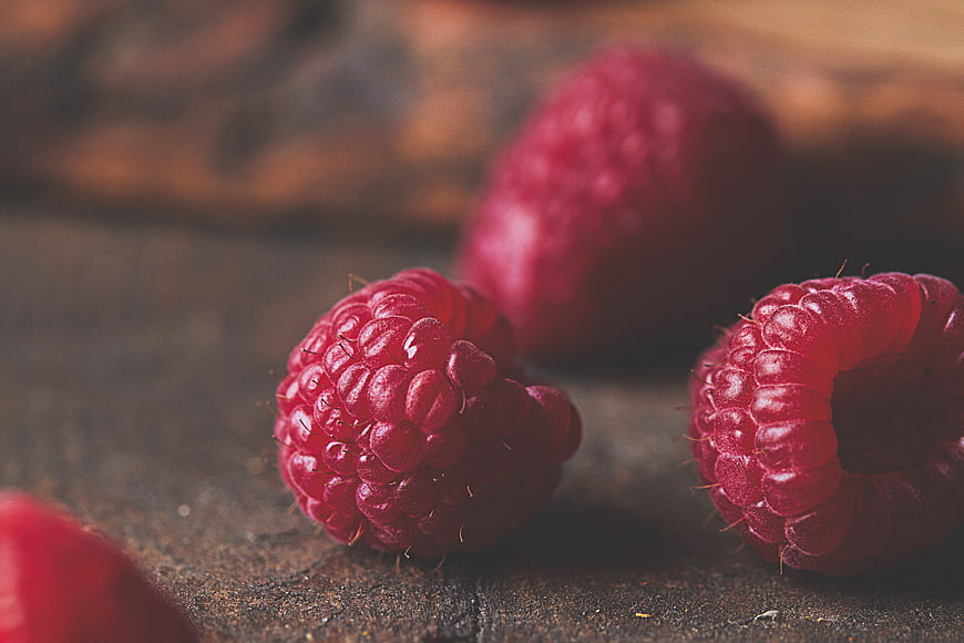 Close-up of fresh raspberries on rustic wooden surface