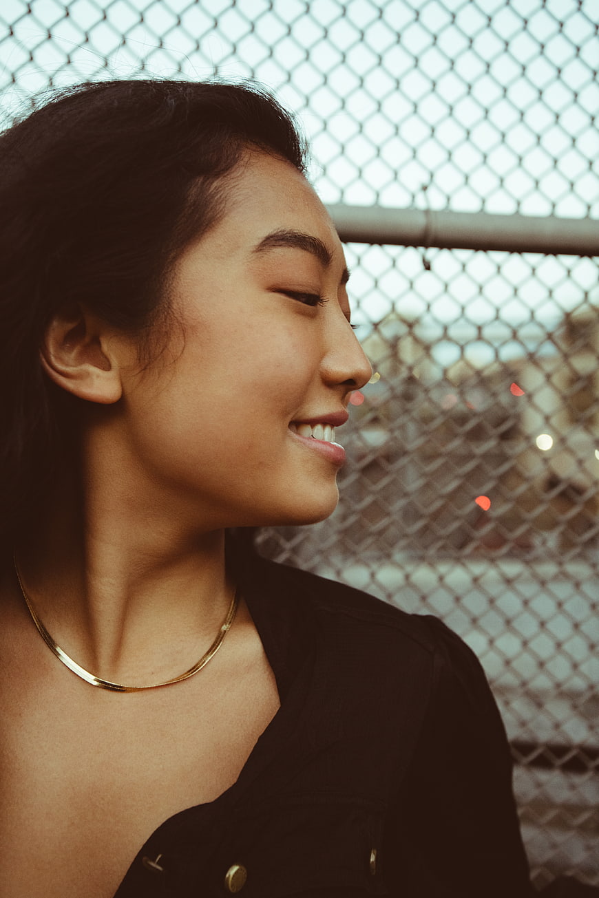 Smiling Asian Woman Profile Portrait Against Chain Link Fence