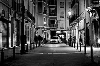 Black and White Night Street Scene with Car and Pedestrians