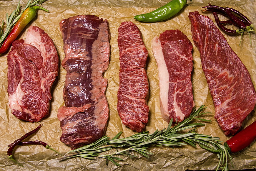 Raw Beef Steaks with Rosemary and Peppers on Brown Paper