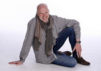 Bald Man Sitting On White Background Wearing Grey Shirt And Scarf