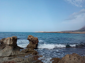 Rugged coastal rocks with crashing waves and distant cliffs