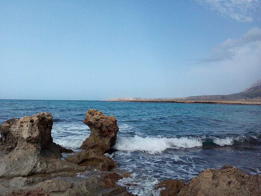 Rugged coastal rocks with crashing waves and distant cliffs