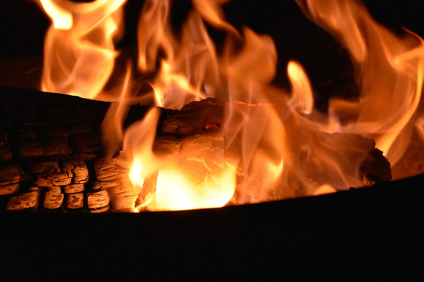 Close-up of burning wood logs in a dark fireplace